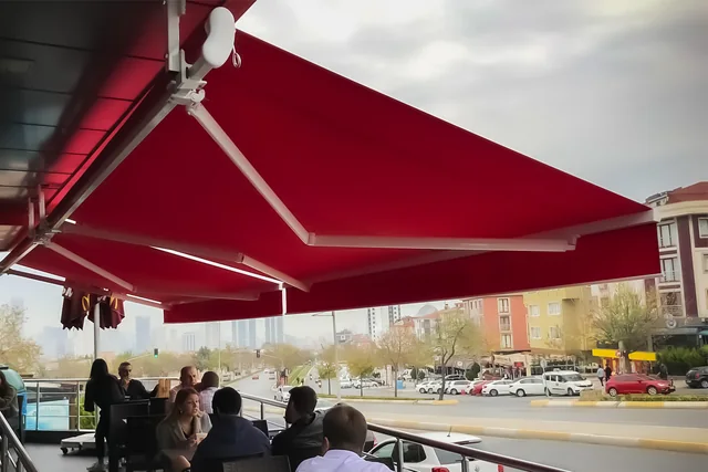 Bordo mafsallı tentenin açılmış kolları ve gölgelendirdiği alan
